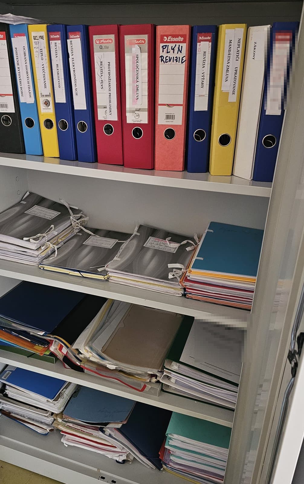 Otvorená kartotéka predsedu SVB: šanóny s popiskami Revízia – výťahy, Plyn revízie, Revízia elektroinštalácie, Revízia – bleskozvod, Protipožiarne prehliadky, Zákony, Poistenie bytového domu.